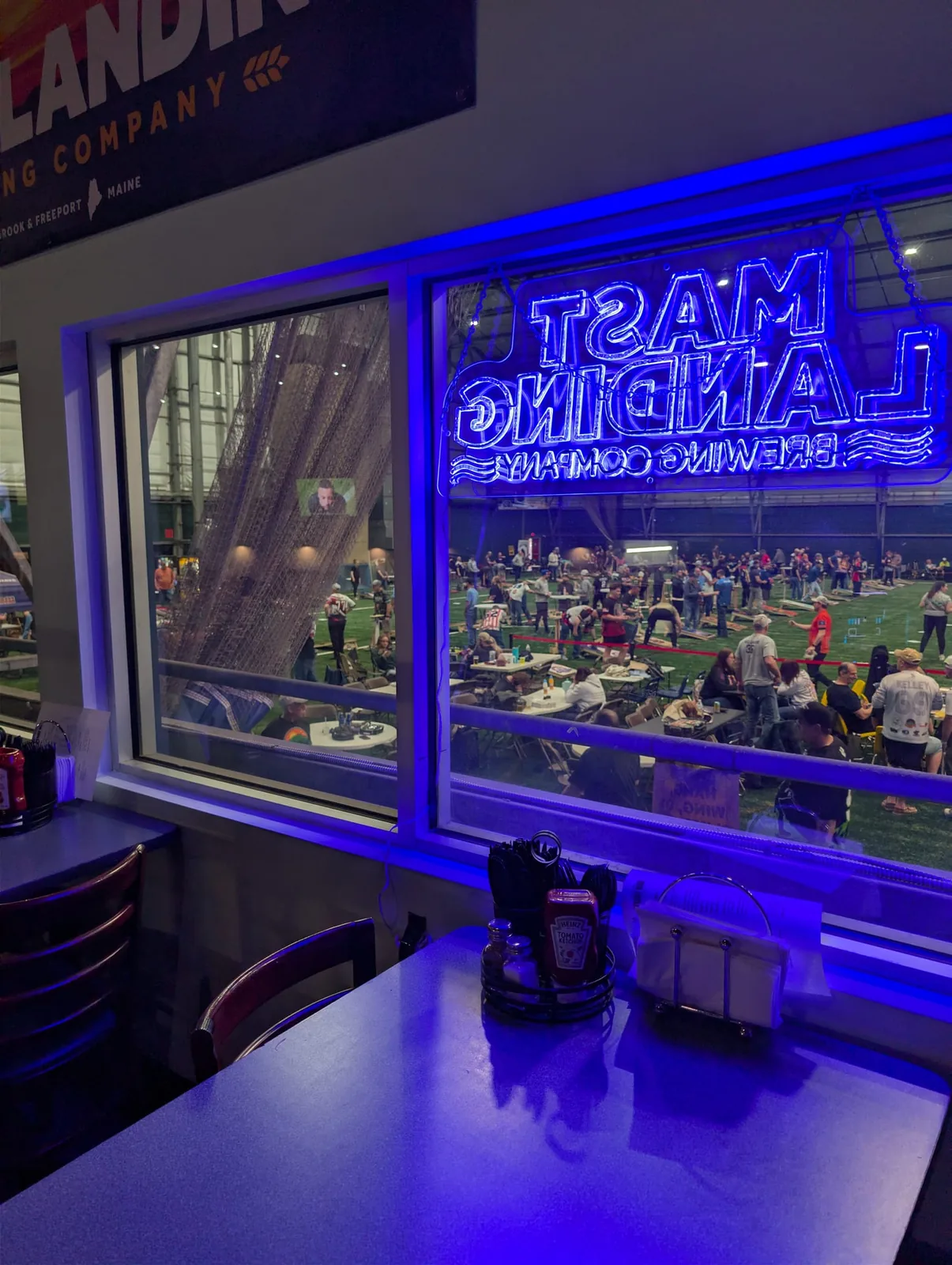 Window onto the sports complex with a Mast Landing Brewing neon sign