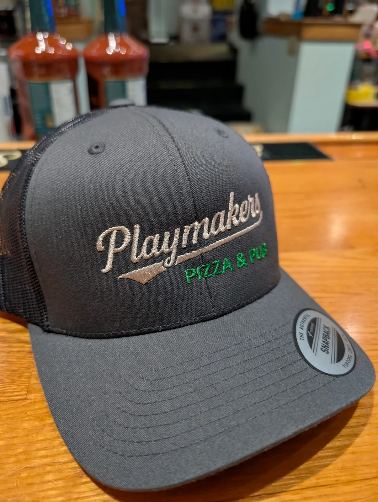 Playmakers Pizza & Pub branded trucker hat on the bar
